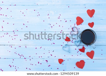 Valentines day and love concept. Close up red hearts with a cup of coffee on light blue wooden background.