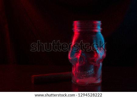 The glass skull smokes a pipe. neon light