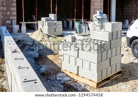 Concrete blocks stacked on pallets outdoors in front of a detached house under construction in the suburbs of Paris, France. Royalty-Free Stock Photo #1294574458