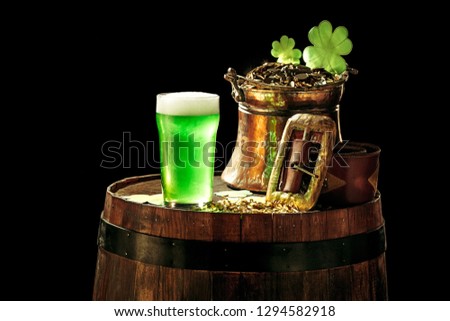 The wooden barrel background with lots of gold coins and a large mug of beer with a green bow. Background for St. Patrick's Day celebration and religious holiday concept