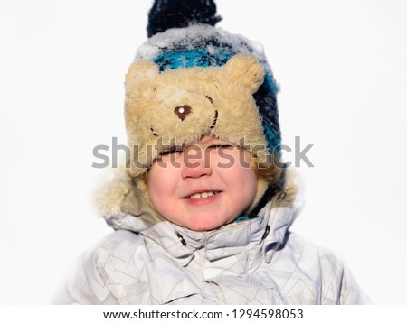  Portrait small child boy having fun wearing a padded jacket and knit hat while playing in the snow.