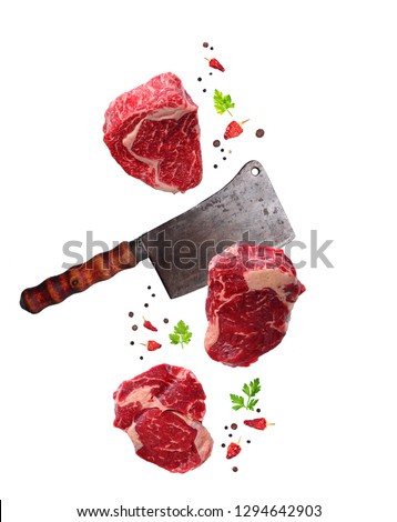 Raw marbled ribeye steak and butchers knife. Food levitation. Isolated on white Royalty-Free Stock Photo #1294642903