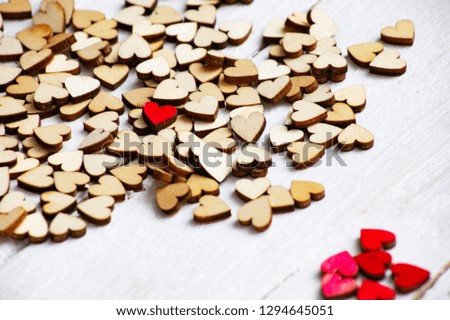 many gray wooden hearts on the white table among them one red heart