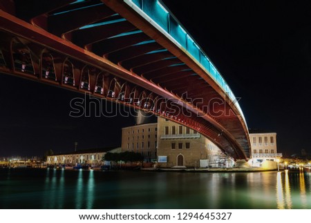 Metal bridge over river at night with reflection