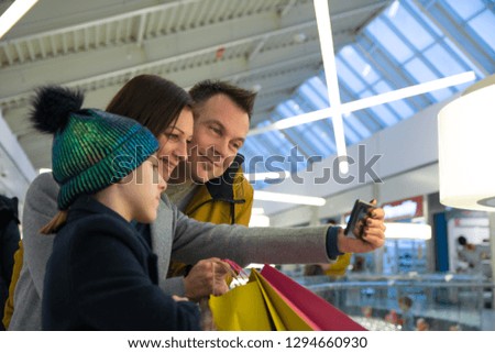 Mother taking picture with her mobile phone of her family in shopping - Image