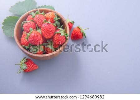 A bowl of beautiful and delicious strawberries isolated on a blue background, closeup, topview, copyspace.
