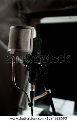 Close up studio condenser microphone with pop filter and anti-vibration mount live recording with black background. Side view