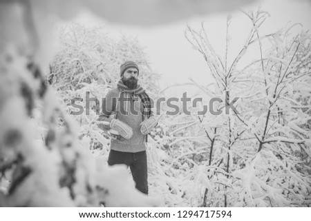 Winter sport and rest, Christmas. skincare and beard care in winter. Man in thermal jacket, beard warm in winter. Temperature, freezing, cold snap, snowfall. Bearded man with skates in snowy forest.