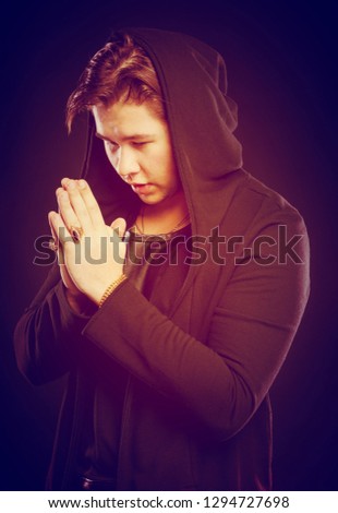Young man praying on a black background