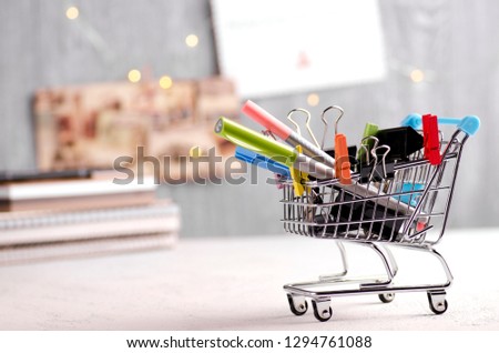 Colorful stationery in a shopping cart, notebooks and greeting cards on the background Royalty-Free Stock Photo #1294761088