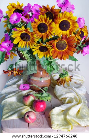 Still life with a bouquet of Sunflowers and ripe apples on the table