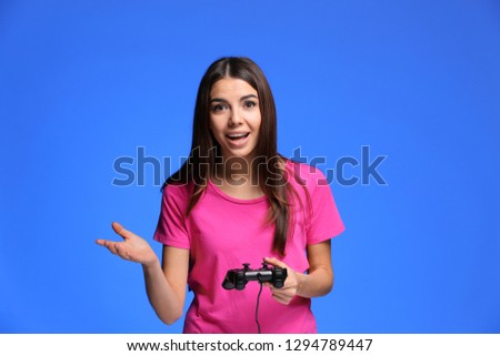 Emotional young woman playing computer game on color background
