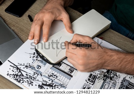 selective focus of mans hands drawing in notebook on wooden table next to album and gadgets