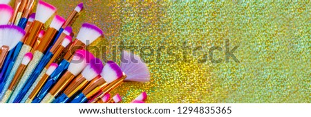 Cosmetics Professional Makeup Brushes on metallic glitter background, close up banner