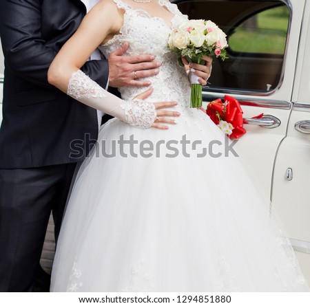Newlyweds are standing near the car