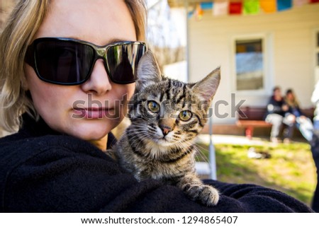 The girl in glasses holds a striped kitten in her arms
