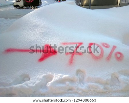 Pointer to 70% discount in the local shop painted on the fresh snow drift in the winter city