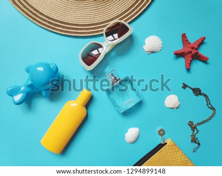Flat lay beach essentials. Sun hat, sunscreen bottle, perfume, seashells and toy dolphin. Summer holidays stuff