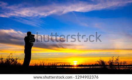 Vivid orange cloud sky.Panorama Sunlight with dramatic sky.Sunset sky began to change from blue to orange.The beautiful cloud on the background of sunset.Silhouette tourists taking pictures of scenery