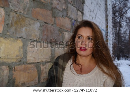 Portrait of a beautiful adult woman on a brick wall background of an old building
