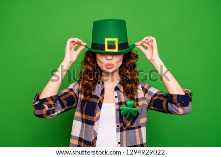 Close up photo of cool attractive she her lady holding hands on cap hiding eyes with it sending kiss to ireland wearing casual checkered plaid shirt leprechaun headwear isolated on green background