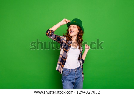 Close up photo of she her wavy brunette sing songs while dancing in bar wearing casual checkered plaid shirt denim jeans leprechaun headwear isolated green vivid bright vibrant background