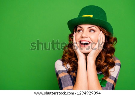 Close up photo of she her curly brunette arms on cheekbones looking to empty space admiring wear casual checkered plaid shirt leprechaun headwear isolated green vivid bright vibrant background