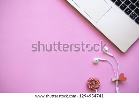 Workspace in pink trendy color. Laptop and headphones close by. Beginning of the holiday or the onset of Valentine's Day or another love event. Near there is a place for text.
