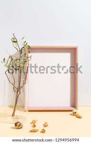 Mock up white frame and branch with green leaves in blue vase on book shelf or desk. Minimalistic concept.