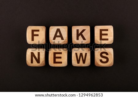 Close up wooden cube signs with FAKE NEWS words over black background with copy space, elevated top view, directly above