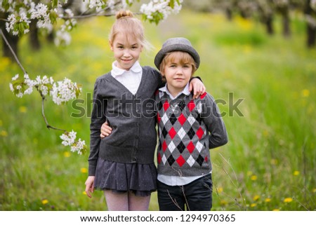 Portrait of a boy in a hat standing against a background of flowering trees.
