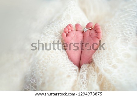 Legs of a newborn baby with mom's wedding ring in a warm white wool rug. Happy Family concept. Beautiful conceptual image of Maternity Royalty-Free Stock Photo #1294973875