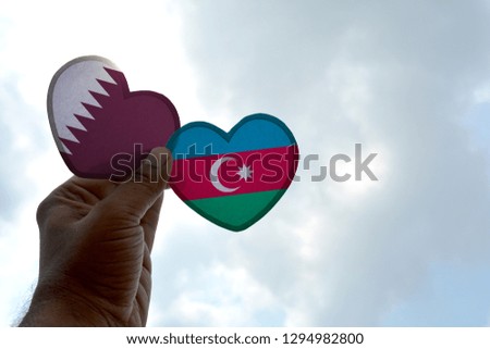 Hand holds a heart Shape Qatar and Azerbaijan flag, love between two countries