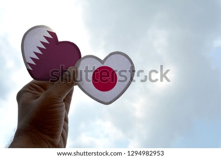 Hand holds a heart Shape Qatar and Japan flag, love between two countries