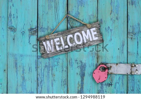 Wood welcome sign hanging on rustic teal blue wooden door with padlock; Valentines Day holiday and love concept background