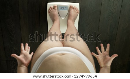 Overweight girl with fat belly standing on scales, word help on screen, angry