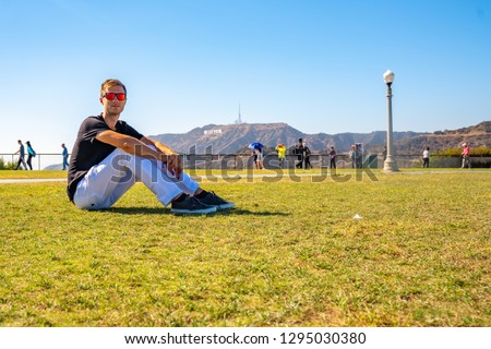 Young man chilling near the Hollywood sign in Los Angeles, USA. Beautiful summer day in California. Great place to admire the skyline of LA.
