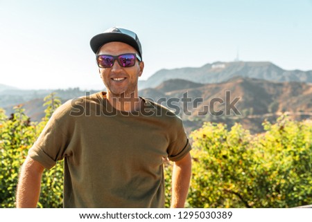 Young man chilling near the Hollywood sign in Los Angeles, USA. Beautiful summer day in California. Great place to admire the skyline of LA.