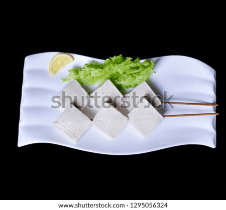 White tofu cubes with vegetables and lemon slices on a white plate