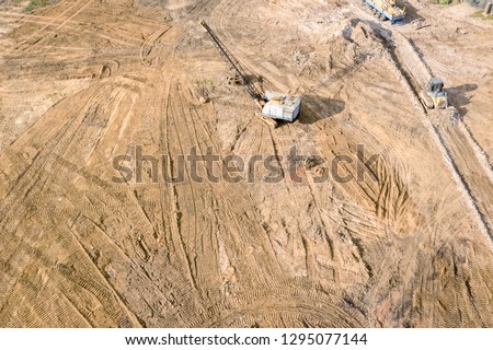 aerial top view of industrial earthmover planing groujnd of constriction site for building works