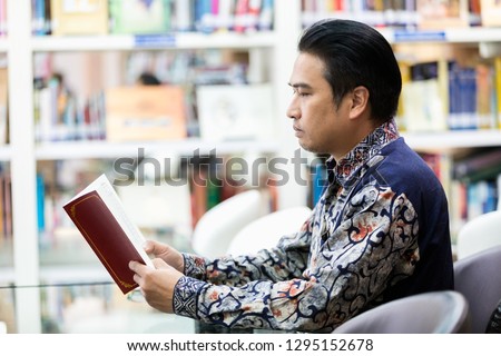 Senior asian man reading with presbyopia in library