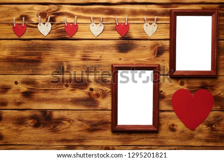 Two empty photo frames hanging on the wooden background with many hearts and garlands. Valentines day concept. Copy space on the left.