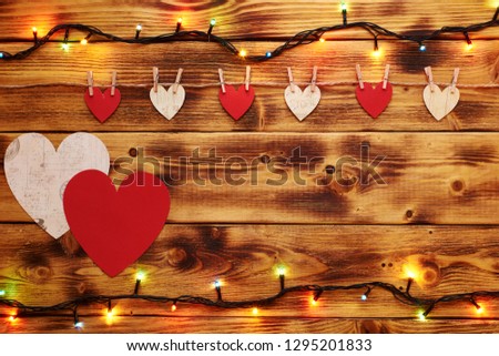 Two big hearts hanging on the wooden background with a few small hearts and garlands. Valentines day concept. Copy space on the right.