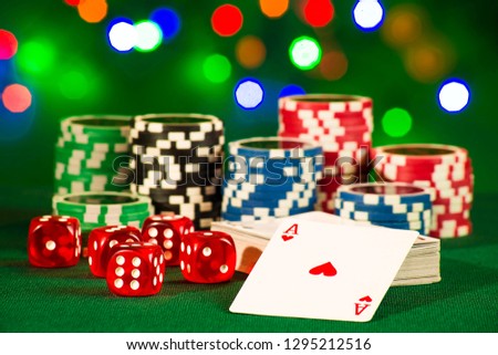 Gambling concept - cards with dices and tokens on green dresses on bokeh lights background