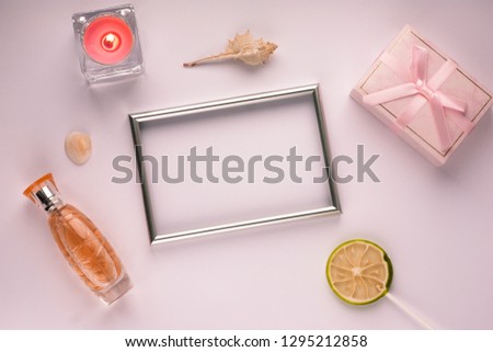 Purple background with frame for photo, gift box, candle and perfume, with empty space