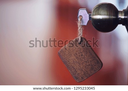Home key with wooden blank house keychain in keyhole, property concept, copy space
