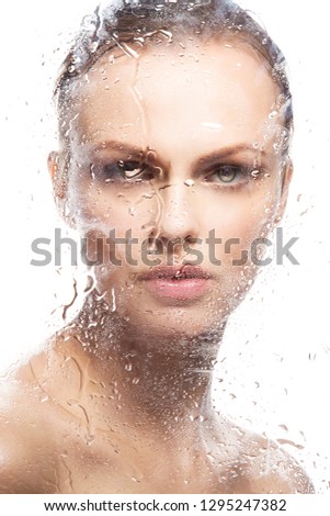 Close-up beauty portrait of fashion model woman with wet skin, natural make-up, near mirror glass with water drops. Attractve face. Skincare facial treatment concept