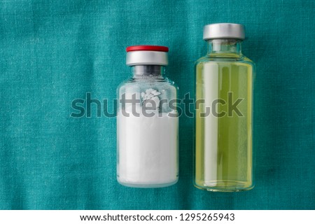 Vials of different size isolated on green cloth, conceptual image