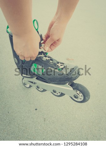 Unrecognizable woman putting on roller skates. Female being sporty having fun during summer in city
