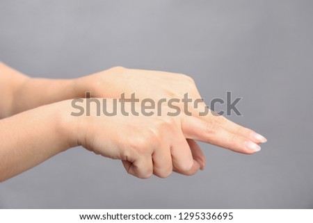 Woman showing word same on grey background, closeup. Sign language